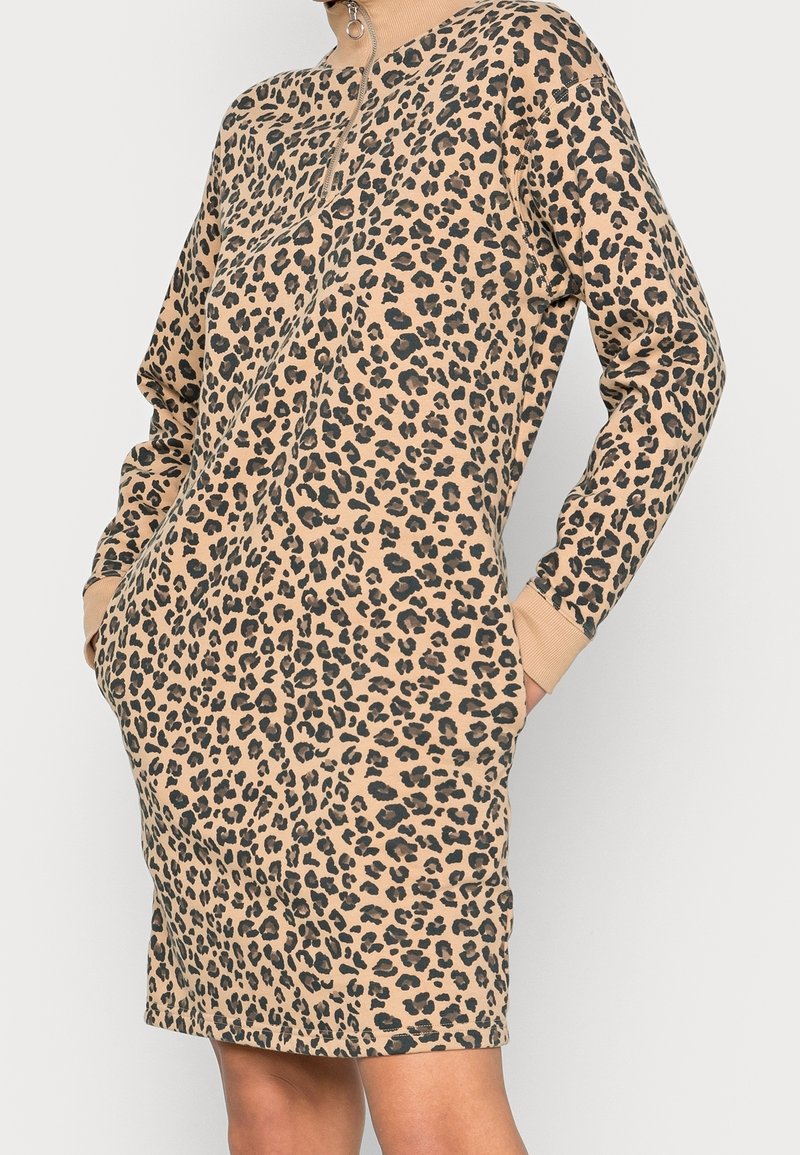 Robe à imprimé léopard beige et noir, manches longues, poches kangourou, tissu doux, longueur mi-cuisse avec un col rond.