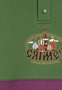 Camisa polo verde con tres botones, que presenta un diseño gráfico colorido de elementos arquitectónicos y texto en varias tipografías. Acento púrpura en la parte inferior.