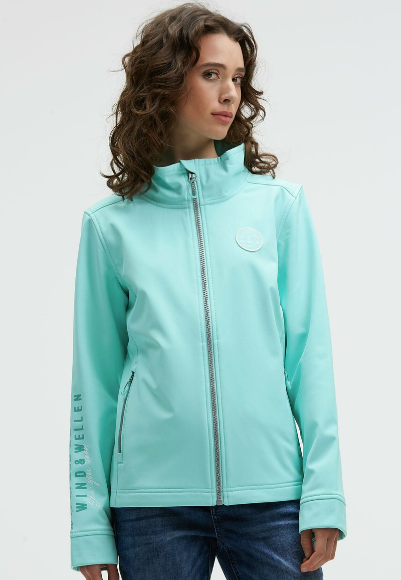 Hellblaues Zip-Jackett mit hohem Kragen, das ein rundes Logo und Text auf dem Ärmel zeigt. Hergestellt aus glattem, geschmeidigem Stoff.