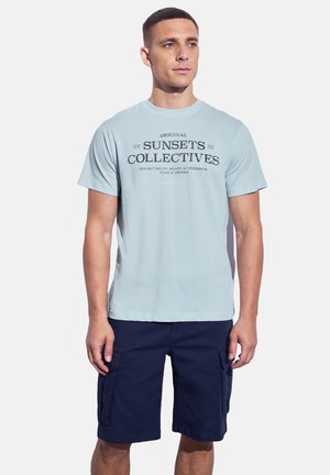 Light blue cotton t-shirt featuring dark print text. Paired with navy cargo shorts, showcasing side pockets and a relaxed fit.