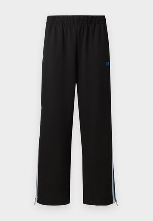 Svarte joggebukser med elastisk midje, sidelommer med glidelås, og blå detaljer på ytterkantene. Glatt stoff med rett ben-design.