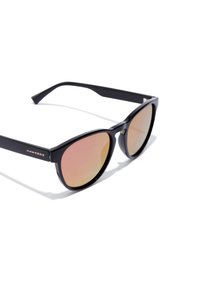 Ochelari de soare din plastic negru cu formă de ochi de pisică, lentile gradient roz și logo-ul "HAWKERS" în aur pe lateral. Finisaj texturat pe rame.