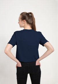 Mörkblå kortärmad t-shirt med rund halsringning, avslappnad passform och slät textur, kombinerad med svarta tajta jeans.