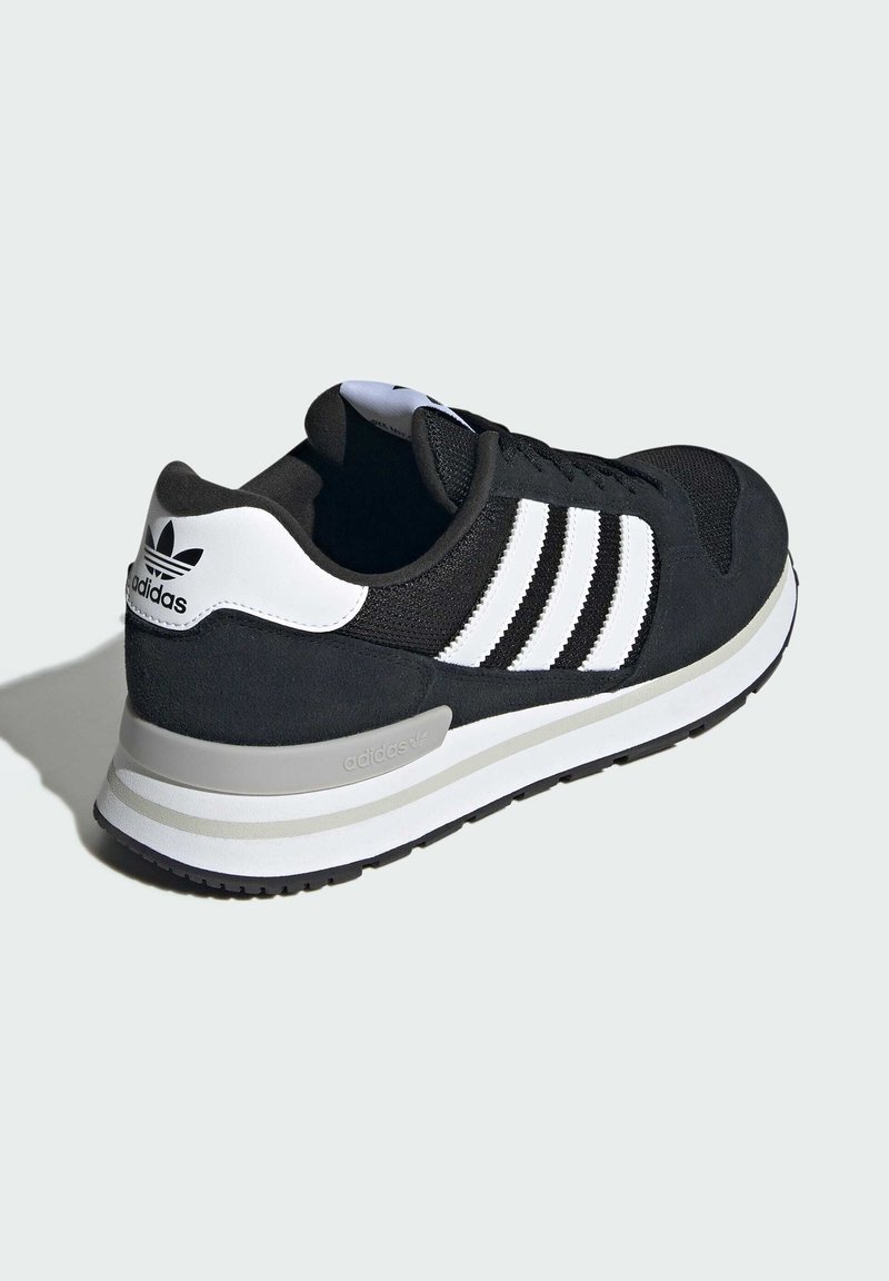 Black and white Adidas sneaker with three white stripes, padded collar, and textured sole shown from rear side angle on plain background.