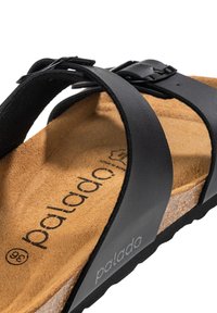 Sandalo nero con una soletta in sughero e una morbida texture in suede. Presenta due fibbie larghe con una chiusura e il nome del marchio "palado" stampato sulla soletta.