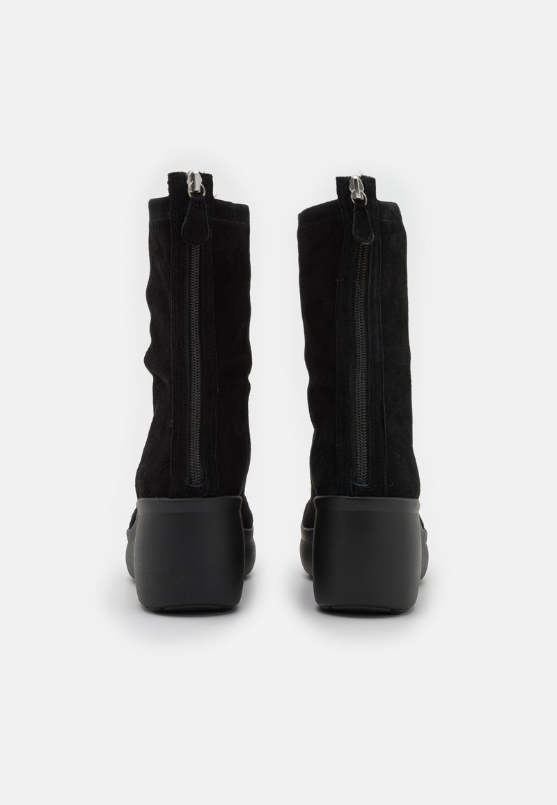 Para czarnych zamszowych botków sięgających do połowy łydki, z tylnymi zamkami i masywnymi obcasami, pokazanych z tyłu na białym tle.