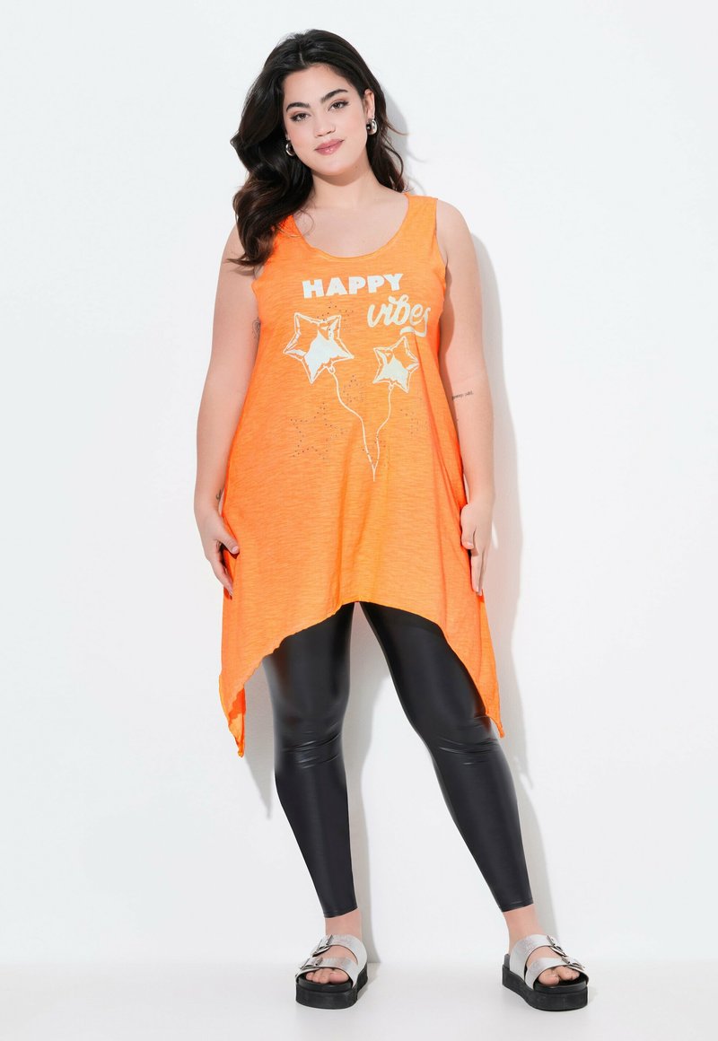 Top sin mangas naranja con un dobladillo asimétrico, que presenta un texto gráfico blanco "HAPPY vibes" y diseños de globos en forma de estrella, combinado con leggings negros.