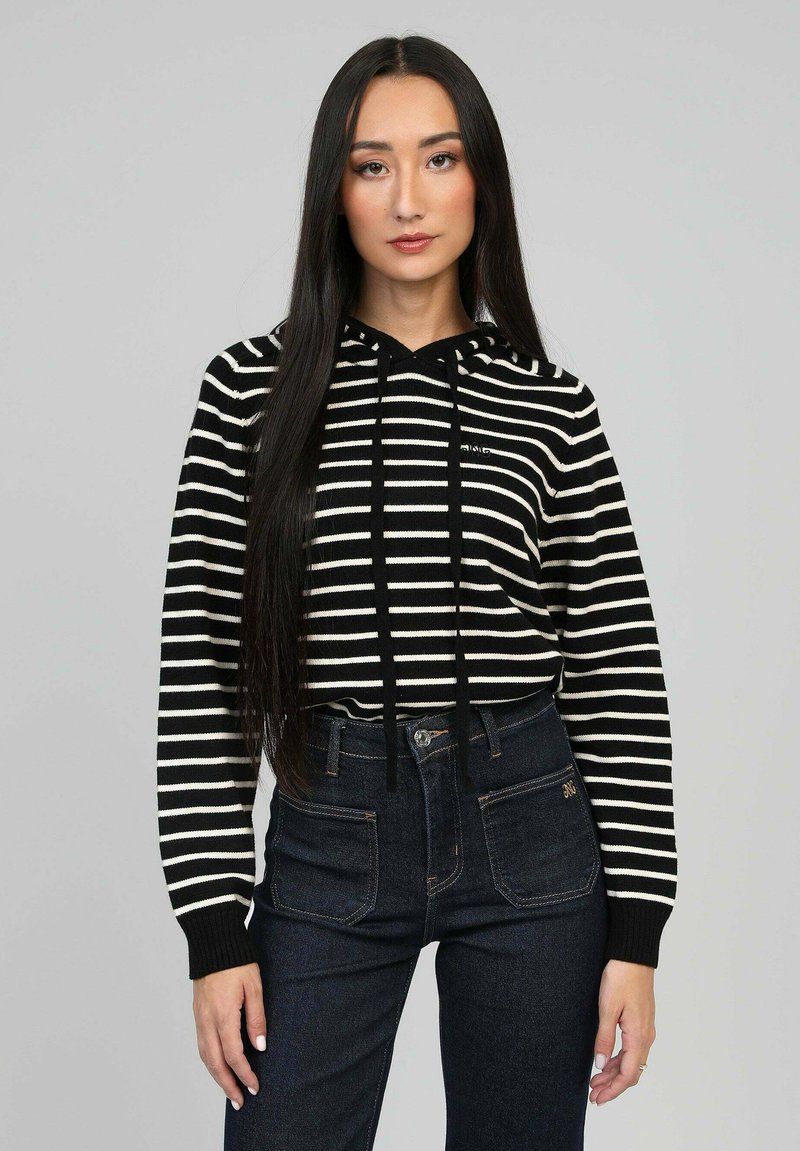 Hoodie rayé noir et blanc avec un cordon de serrage, des poignets côtelés et une coupe décontractée, associé à un jean en denim foncé taille haute.