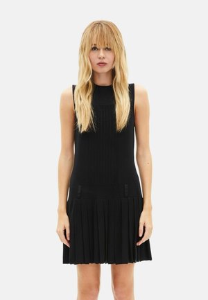 Schwarzes ärmelloses Kleid mit plissiertem Rock und strukturiertem Oberteil. Verfügt über vertikale Streifen und zwei kleine Schleifenakzente in Taillennähe.