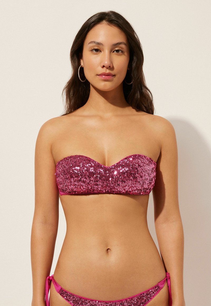 Rosa paljetterad bandeau-bikinitopp med en slät yta, som har en söt hjärtformad halsringning. Matchas med matchande knutna bikinitrosor.