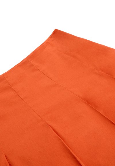 Primer plano de una tela naranja con líneas de costura visibles que forman secciones rectangulares y anguladas.