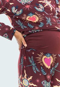 Conjunto de color marrón con un patrón que presenta libélulas, corazones y diseños florales; hecho de un material suave y flexible con un detalle fruncido en la cintura.