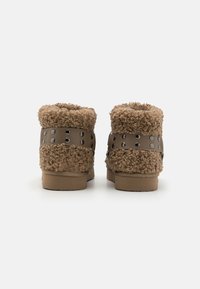 Bruna, texturerade ankelskór med en fluffig ovandel och en slät sidoband prydd med svarta nitar, med en låg, platt sula.