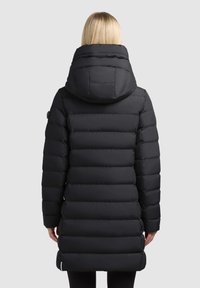 Black puffer coat with a hood, featuring horizontal quilting, long sleeves, and a slightly longer back. Soft material with a smooth texture.