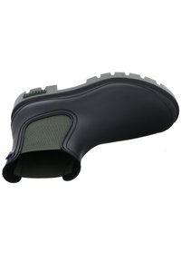 Botín de goma negro hasta el tobillo con un panel de tela verde texturizada, suela gris resistente con tacos pronunciados y cierre lateral con cremallera.