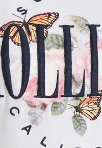 Black embroidered letters over pastel floral print with two orange and black butterflies on white fabric.