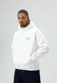Witte hoodie met een voorzak en blauwe logo-accenten. Gemaakt van een zachte stof, met geribbelde manchetten en zoom. Casual pasvorm.