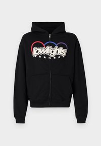 Sweat à capuche noir zippé avec poche kangourou à l'avant, poignets côtelés, et un motif graphique du mot « lowlights » entouré d'anneaux colorés et d'étoiles.