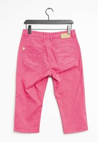 Jean cropped rose avec une texture lisse, cinq poches et une étiquette en cuir à la taille arrière. Suspendu à un cintre en plastique noir.