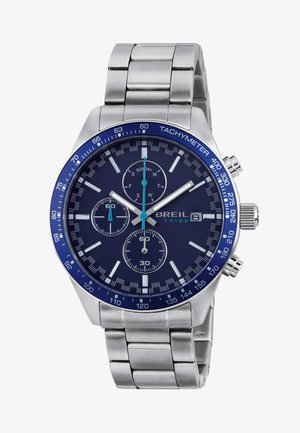 Sølv metal ur med blå tachymeter bezel, tre subdials, datovindue og blå urhænder, der viser tiden som 10:08:00.