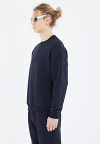 Marineblauer Sweatshirt mit gerippten Bündchen und Saum, aus weichem Baumwollmaterial gefertigt. Mit Rundhalsausschnitt und dezenten Logodetails.