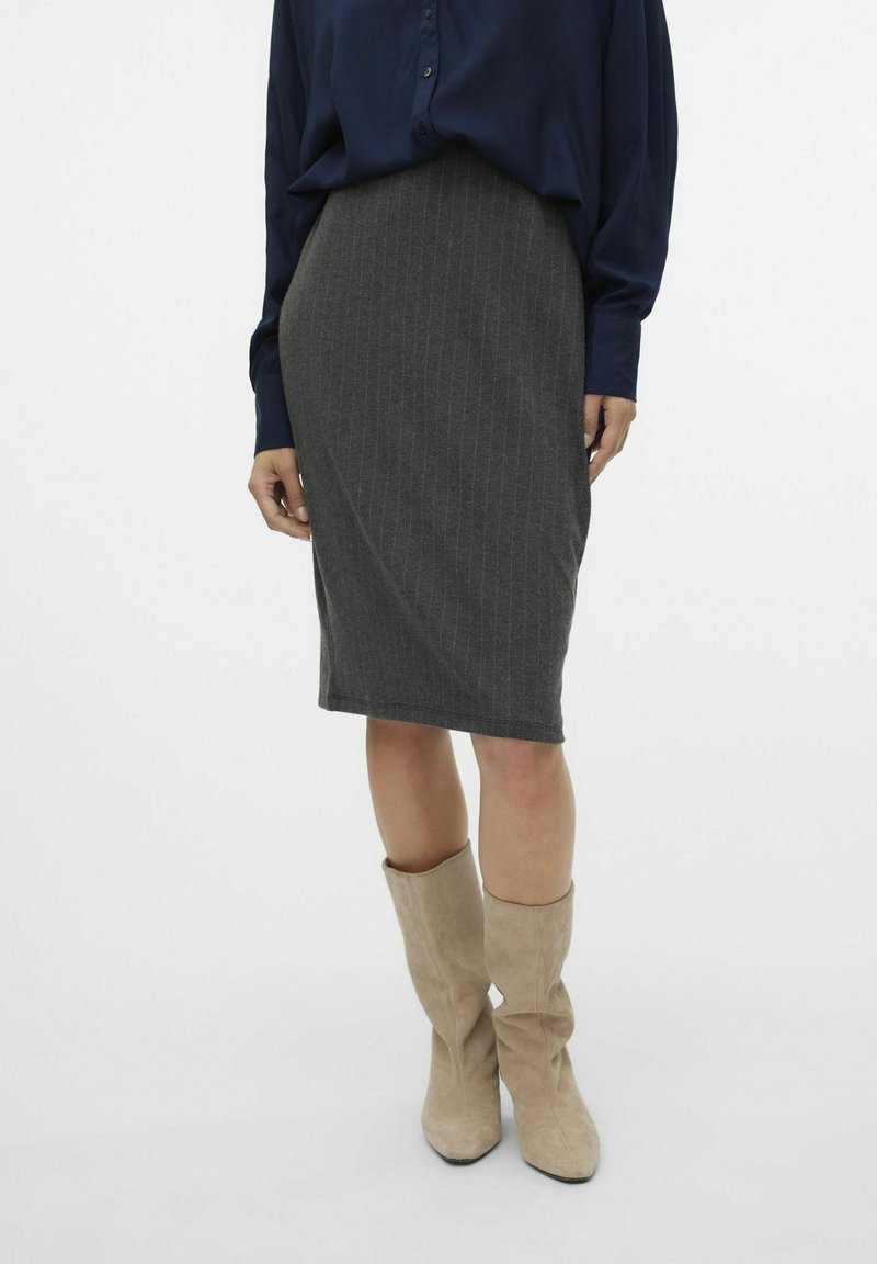 Donkergrijze kokerrok met verticale streepjes, gemaakt van textuurstof. Gecombineerd met een marineblauw shirt en lichtbeige kniehoge laarzen.