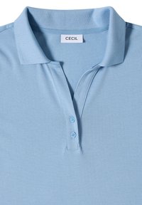 Polo bleu clair avec col plié, deux boutons sur la patte et une petite étiquette à l'intérieur du col indiquant "CECIL".