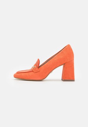 Mocasín de ante naranja con tacón alto, punta cuadrada, un acento de rayas diagonales y una hebilla metálica decorativa. Superficie texturizada, tacón grueso y resistente.