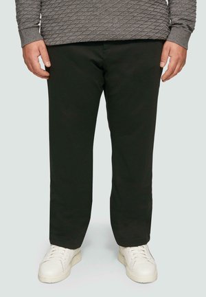 Donkergroene broek van gladde stof, met een rechte snit en gecombineerd met witte sneakers. Geen duidelijke patronen of hardware zichtbaar.