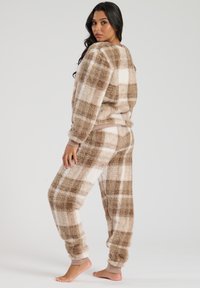 Flauschiges Zweiteiler-Lounge-Set in beige-braunem Karomuster. Mit elastischen Bündchen und einem dehnbaren Bund, weichem Material und lockerer Passform.