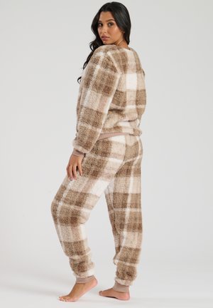 Fuzzy lounge set bestaande uit twee delen in een beige en bruine geblokte patroon. Voorzien van elastische boorden en tailleband, zachte textuur en een relaxte pasvorm.