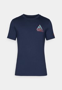 Camiseta de manga corta azul marino hecha de algodón con un cuello redondo. Presenta un logotipo geométrico en rojo y azul en el lado izquierdo del pecho.