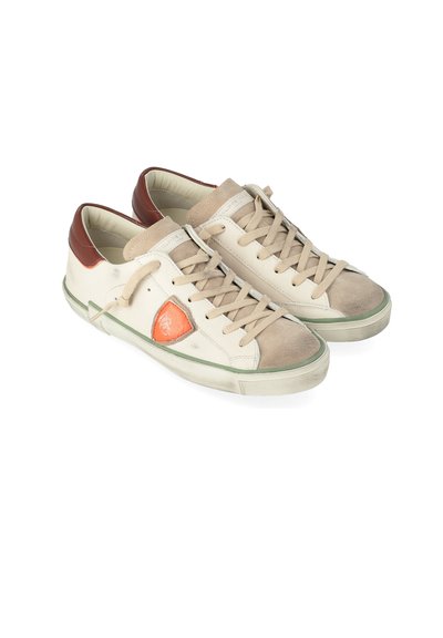 Un paio di sneakers basso beige e marroni con lacci, patch arancione sui lati e suole bianche leggermente usurate su uno sfondo bianco.