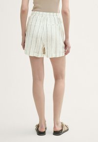Vita randiga shorts med elastisk midja, med sidofickor och en mjuk yta, kombinerat med ljusa slidesandaler.
