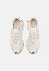 A fehér suede és hálós sneakers texturált felsőrésszel, illeszkedő fűzővel, megerősített sarokkal és barna gumitalppal rendelkezik. Oldalt márkával ellátva.