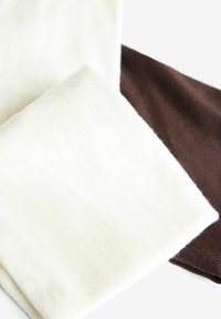 Kaksi taitettua kangaspalaa: toinen off-white, pehmeä tekstuuri, ja toinen tummanruskea, sileä pinta, molemmat suorakulmaisen muotoisia.
