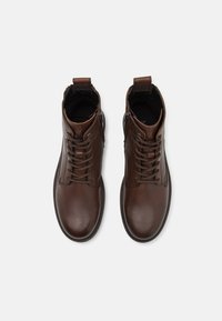 Brune lær ankle boots med rund tå, snørebånddesign og glidelås på siden. Glatt tekstur med minimal søm og en pull-tab.