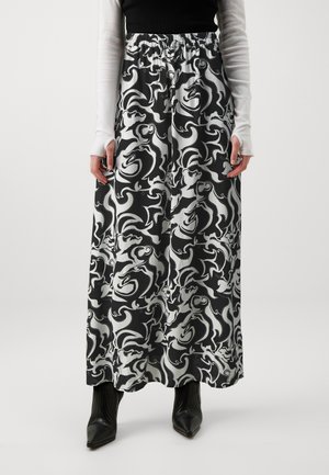 Gonna maxi con un motivo a spirale bianco e nero, cintura elastica, tessuto leggero, abbinata a stivaletti neri con punta.