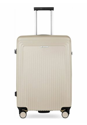 Valise rigide beige avec des rainures verticales, quatre roues pivotantes et une poignée télescopique noire déployée.