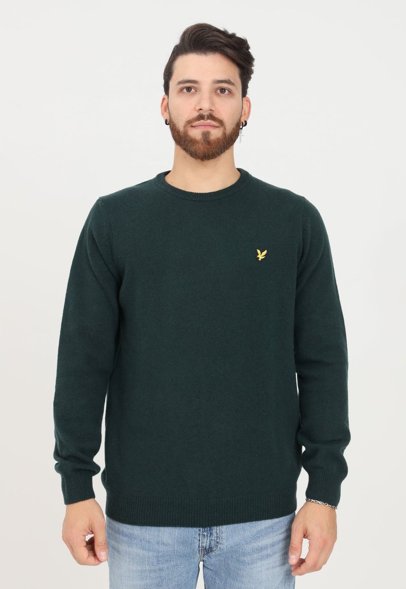 Maglione verde realizzato in morbido tessuto a maglia, con colletto a girocollo e polsini aderenti, e un piccolo logo giallo sul petto.