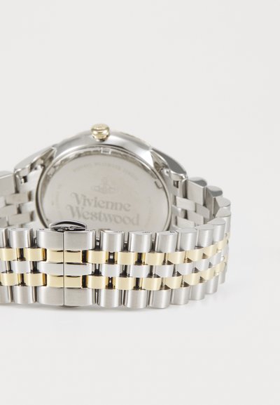Hõbedane ja kuldne metallist randmekell, millel on lingitud kellarihm, ümmargune korpus, kroon ja graveeritud tagakülg, millel on Vivienne Westwoodi logo.