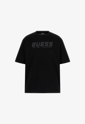 Fekete pamut póló, kerek nyakkivágással és rövid ujjakkal. Elöl egy nagy, sötétszürke "GUESS" logó található, amely mellett az alapítás dátuma is szerepel.