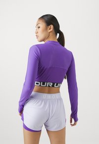 Lilla langermet topp med en tettsittende design og kontrastfarget svart logobånd. Kombinert med lyse lilla shorts med en subtil detalj.