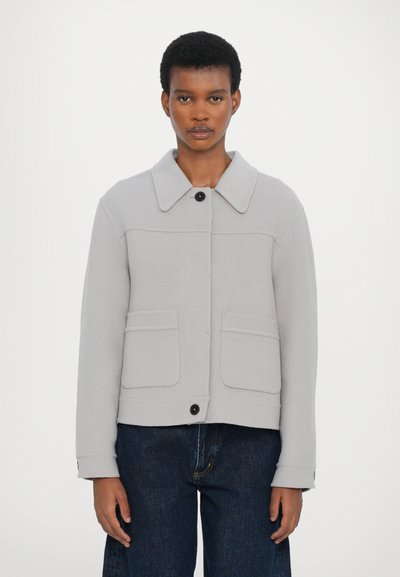 Veste gris clair en tissu doux, dotée d'un col large, de deux poches avant, d'une fermeture à boutons sur le devant et de manches longues.