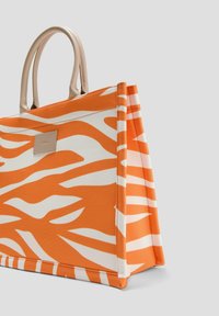 Orange-weiße Baumwoll-Tasche mit Zebra-Streifen-Muster, ausgestattet mit beigefarbenen Ledergriffen und einer rechteckigen Form.