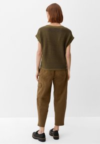 Olive green knitted top with short sleeves and textured stripes, paired with brown cargo pants and black platform shoes.