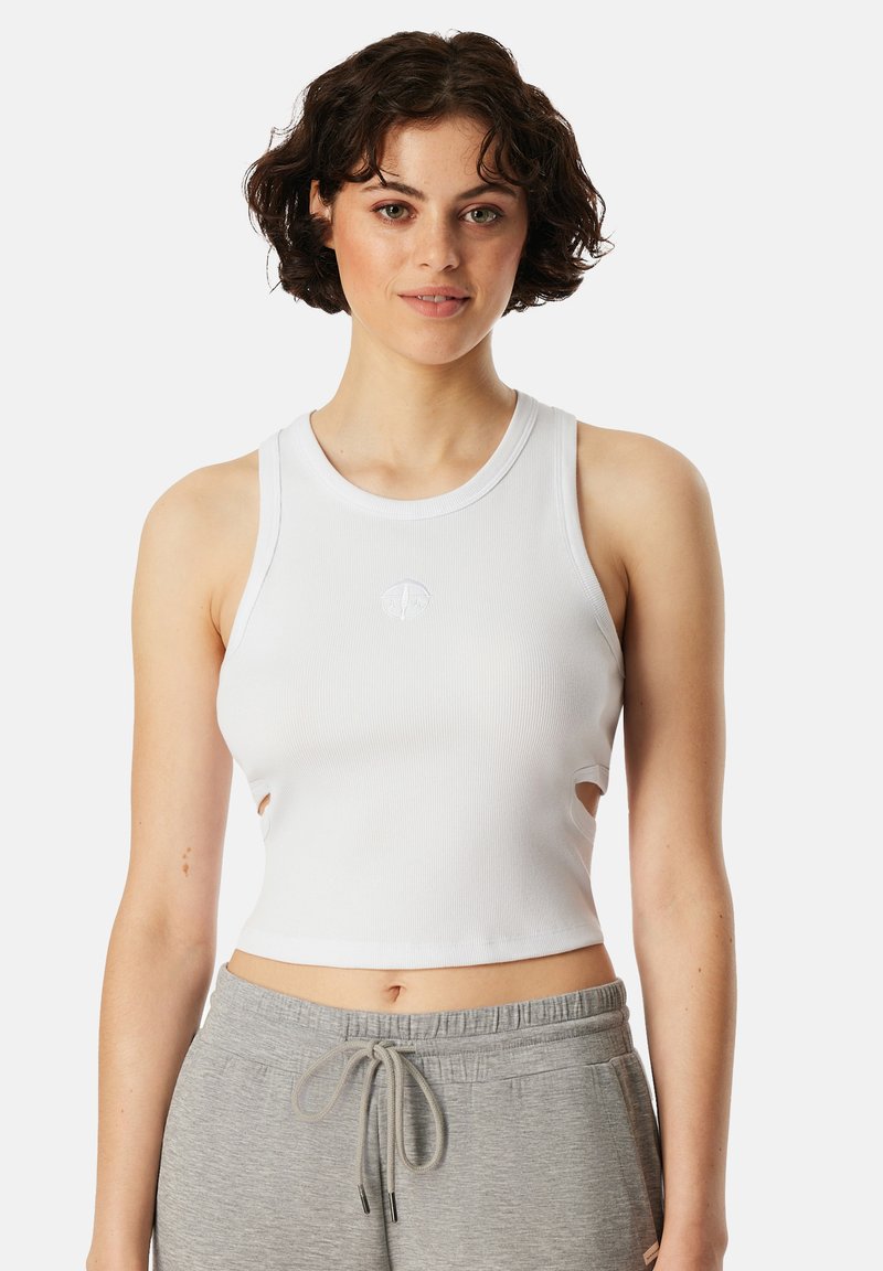 Bílý žebrovaný crop top s výřezy na stranách a malým logem na hrudi. Materiál má hladkou texturu.