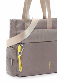 Sac fourre-tout beige texturé avec doubles anses, poche avant zippée, tirette de fermeture éclair jaune avec clip métallique, et petite poche latérale.
