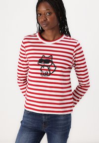 Red and white striped long-sleeve shirt featuring a graphic of a cat in sunglasses. Soft fabric with a round neckline and relaxed fit.