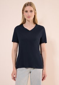 Námořnická modrá krátkosrstá tričko s V-výstřihem vyrobené z měkké tkaniny, s uvolněným střihem a minimalistickým designem bez vzorů nebo ozdob.